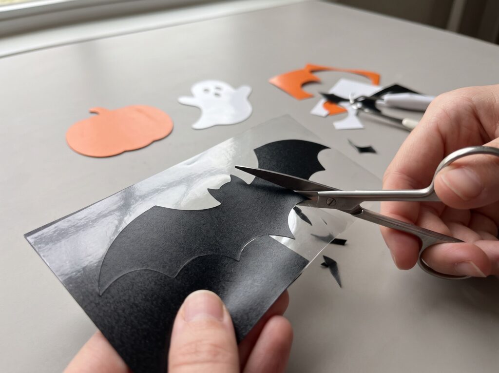 Decupare de mână a unui liliac din folie termotransfer neagră, cu foarfeca de precizie, pentru stickere textile de Halloween